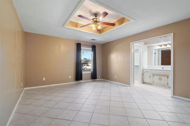 unfurnished bedroom with sink, a raised ceiling, connected bathroom, ceiling fan, and light tile patterned floors