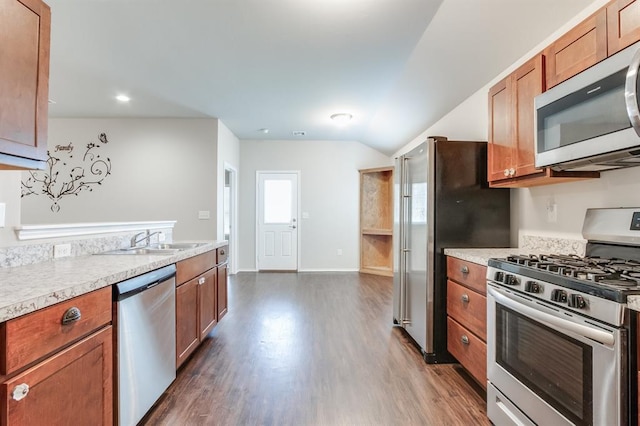 kitchen featuring dark wood-type flooring, sink, appliances with stainless steel finishes, and lofted ceiling