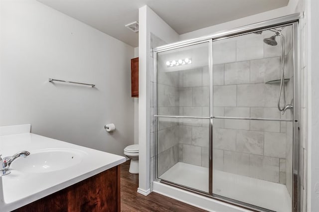 bathroom featuring toilet, vanity, an enclosed shower, and hardwood / wood-style floors