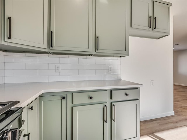 kitchen featuring stove, backsplash, and light hardwood / wood-style flooring