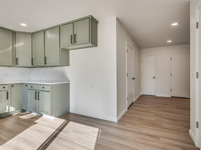 kitchen with tasteful backsplash, green cabinetry, and light hardwood / wood-style floors