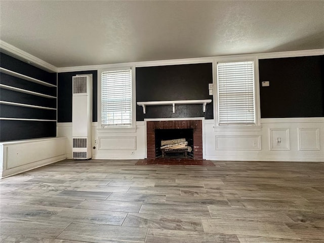 unfurnished living room with a brick fireplace, crown molding, and hardwood / wood-style flooring