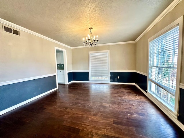 empty room featuring dark hardwood / wood-style flooring, ornamental molding, a wealth of natural light, and a notable chandelier