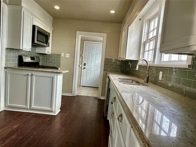 kitchen with stainless steel appliances, light stone counters, plenty of natural light, sink, and white cabinetry