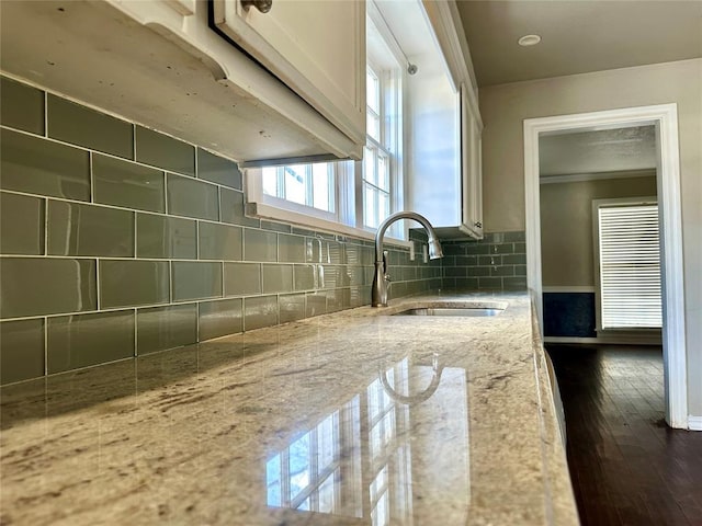 kitchen featuring sink, dark hardwood / wood-style flooring, light stone countertops, and tasteful backsplash