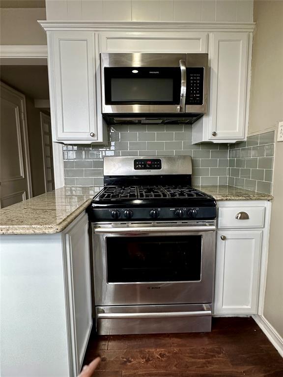 kitchen with stainless steel appliances, white cabinetry, dark hardwood / wood-style floors, and light stone countertops