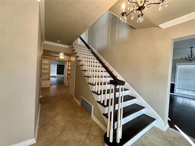 stairway featuring tile patterned flooring, a textured ceiling, a chandelier, and crown molding