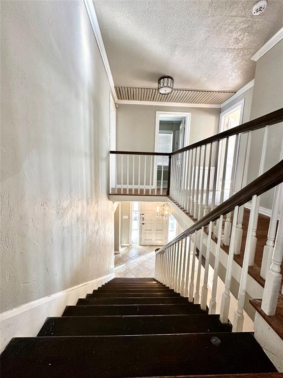 staircase with a textured ceiling and ornamental molding