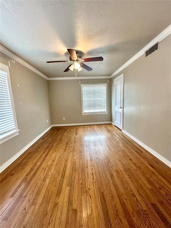 unfurnished room with a textured ceiling, ceiling fan, crown molding, and wood-type flooring