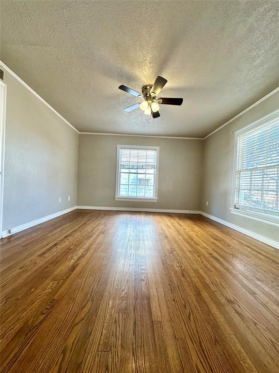 unfurnished room with a textured ceiling, ceiling fan, crown molding, and wood-type flooring