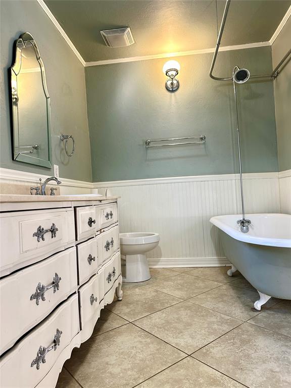 bathroom featuring a bathing tub, toilet, tile patterned floors, vanity, and crown molding