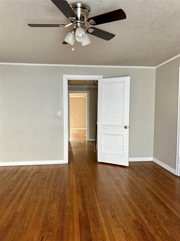 unfurnished room featuring ornamental molding, dark wood-type flooring, a textured ceiling, and ceiling fan