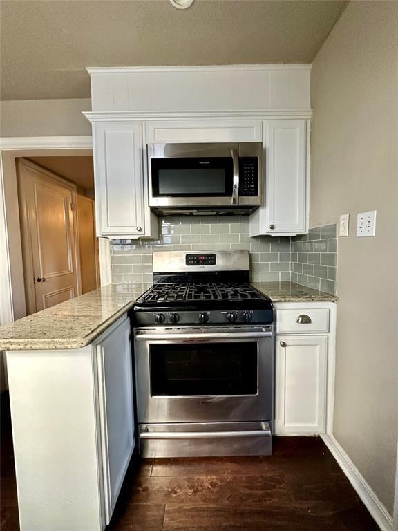 kitchen featuring light stone countertops, dark wood-type flooring, appliances with stainless steel finishes, and white cabinetry