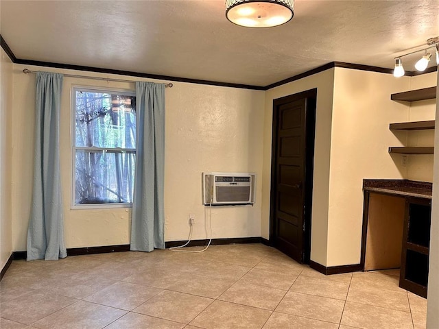 spare room with a wall unit AC, a textured ceiling, light tile patterned floors, and crown molding