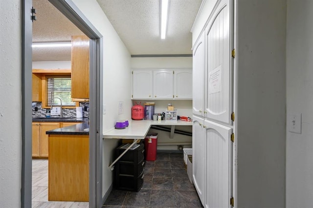 kitchen featuring sink, a textured ceiling, white cabinets, and tasteful backsplash