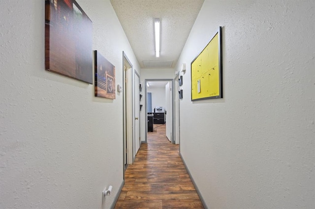 corridor featuring a textured ceiling and dark hardwood / wood-style flooring