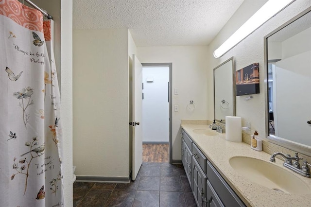 bathroom featuring toilet, vanity, a textured ceiling, and curtained shower