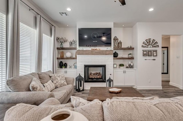 living room with ceiling fan, dark wood-type flooring, and a brick fireplace