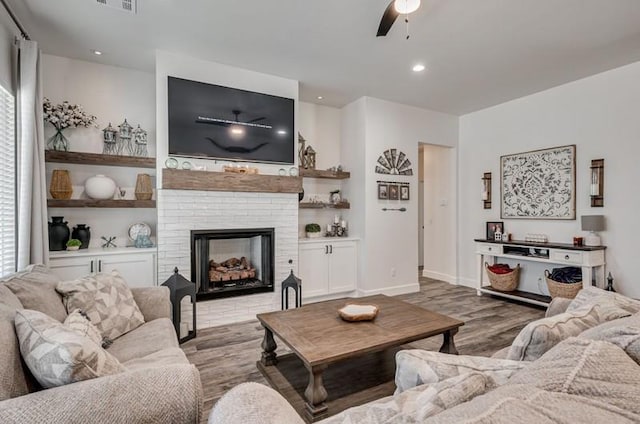 living room with a brick fireplace, ceiling fan, and light hardwood / wood-style floors