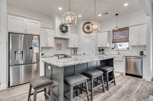 kitchen featuring pendant lighting, a center island, white cabinets, appliances with stainless steel finishes, and sink