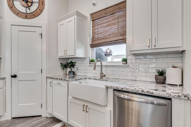 kitchen with sink, light stone countertops, dishwasher, and white cabinetry