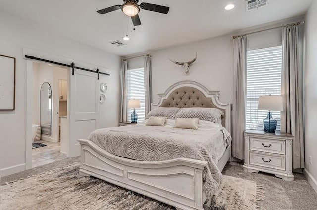 bedroom with ceiling fan, multiple windows, light carpet, and a barn door