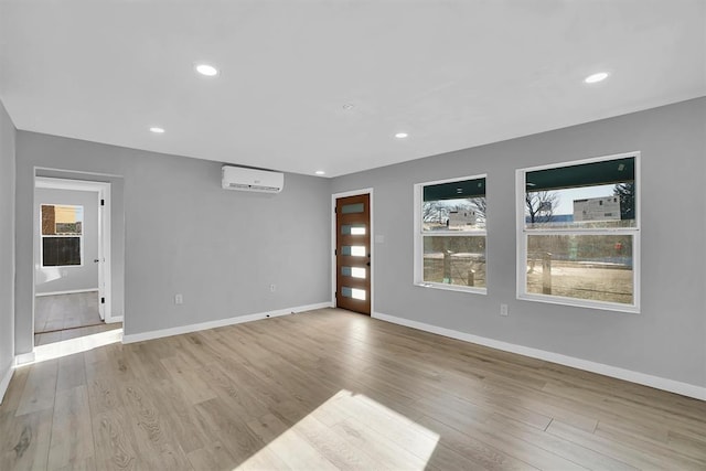 empty room with light wood-type flooring and an AC wall unit