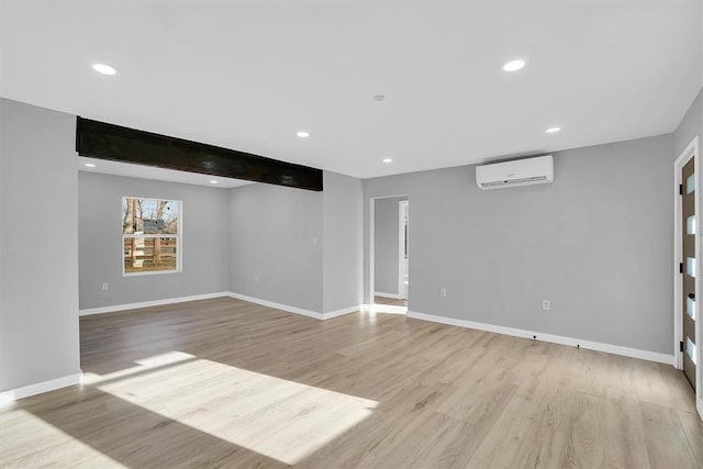 interior space with light hardwood / wood-style flooring, beamed ceiling, and an AC wall unit