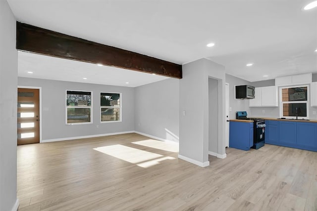 unfurnished living room with sink, light hardwood / wood-style flooring, and beamed ceiling