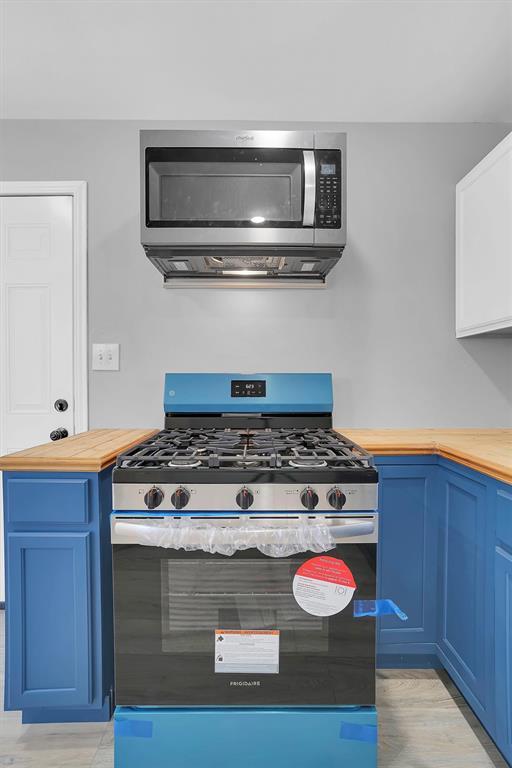 kitchen featuring butcher block countertops, stainless steel appliances, and blue cabinets