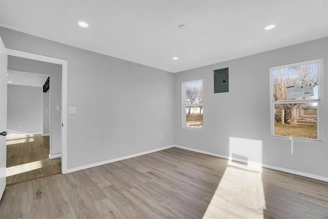 spare room featuring electric panel and light hardwood / wood-style flooring