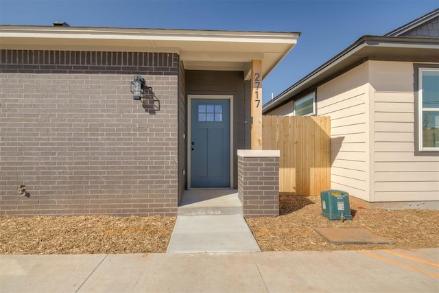 property entrance featuring brick siding and fence