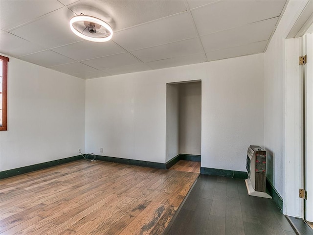 spare room featuring heating unit and dark hardwood / wood-style floors