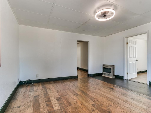 empty room featuring wood-type flooring, a wood stove, and heating unit