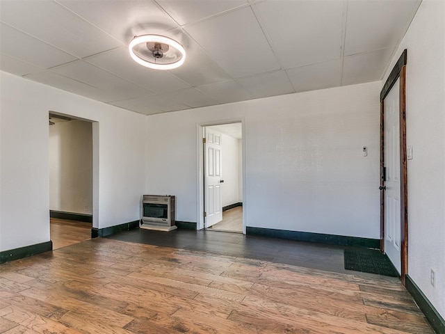 unfurnished room with hardwood / wood-style flooring, a wood stove, and heating unit