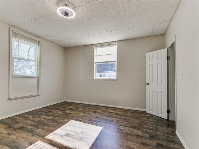 spare room with dark wood-type flooring and a paneled ceiling