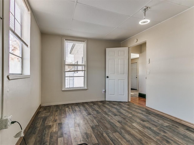 unfurnished room with a drop ceiling and dark hardwood / wood-style flooring