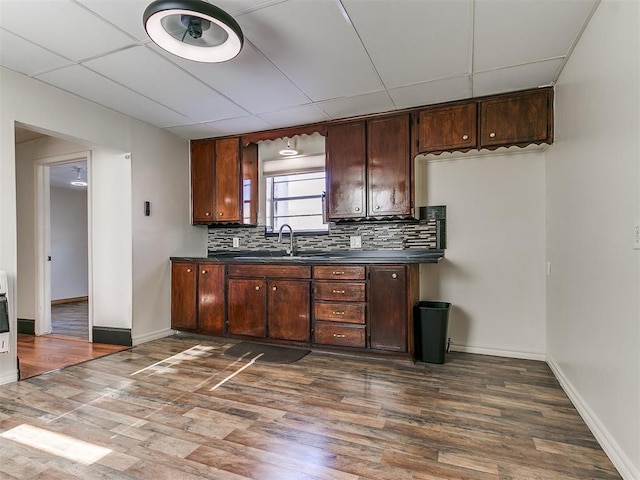 bar with dark hardwood / wood-style floors, backsplash, a paneled ceiling, and sink