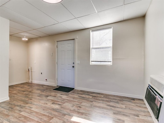 interior space featuring hardwood / wood-style floors, a paneled ceiling, and heating unit