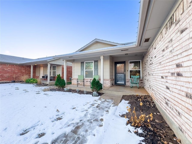 snow covered property entrance featuring covered porch