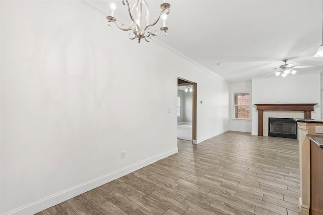 unfurnished living room featuring ceiling fan with notable chandelier, crown molding, and light hardwood / wood-style floors