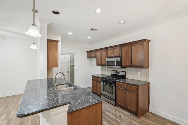 kitchen with pendant lighting, appliances with stainless steel finishes, sink, ornamental molding, and light hardwood / wood-style flooring