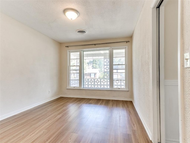 empty room featuring a textured ceiling and light hardwood / wood-style flooring