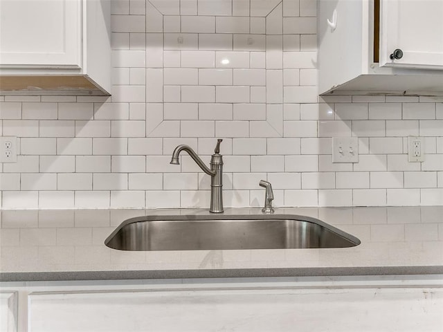 kitchen with sink, white cabinetry, light stone counters, and backsplash