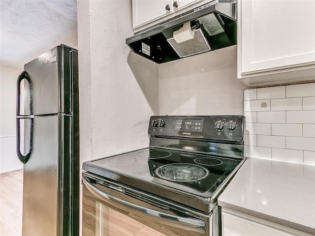 kitchen with black appliances, light hardwood / wood-style floors, decorative backsplash, white cabinetry, and exhaust hood