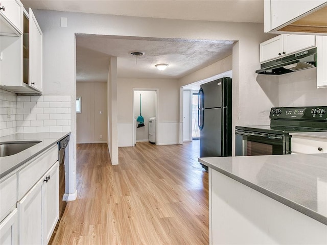 kitchen with washer / clothes dryer, white cabinetry, light hardwood / wood-style flooring, backsplash, and black appliances