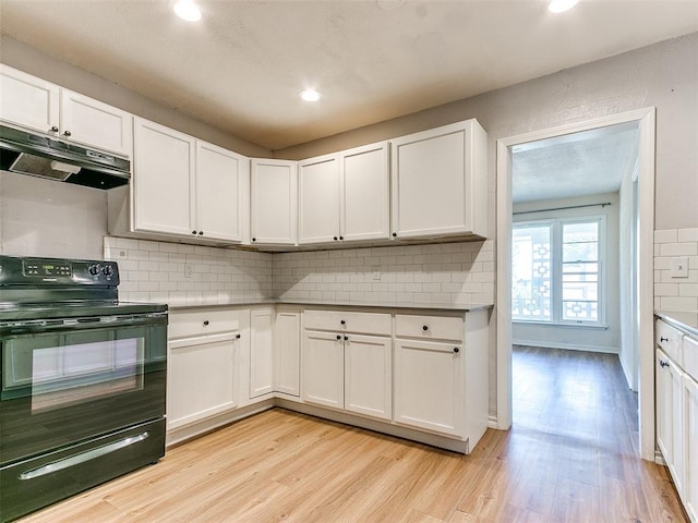 kitchen with white cabinets, light hardwood / wood-style floors, decorative backsplash, and black electric range oven