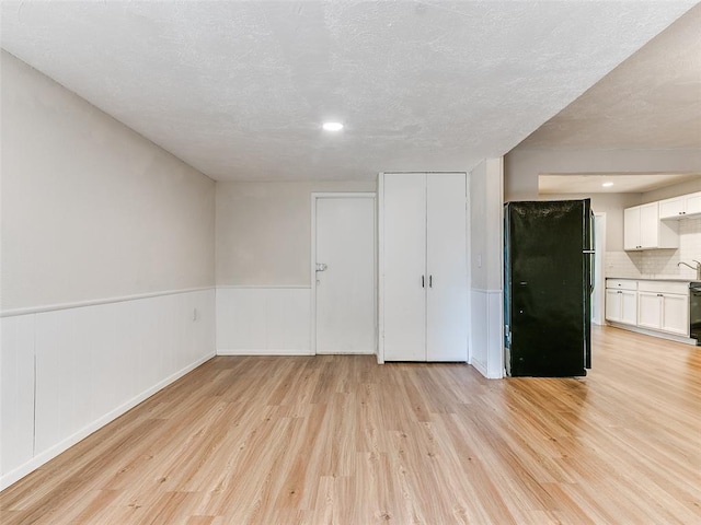 spare room featuring light wood-type flooring and a textured ceiling