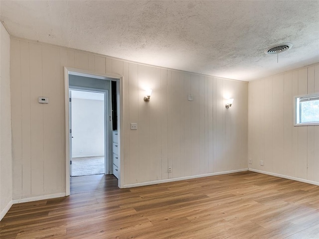 spare room featuring a textured ceiling and light wood-type flooring