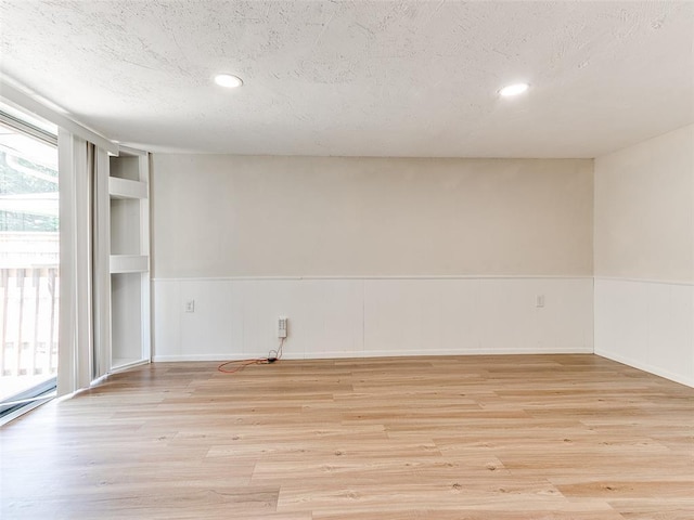 spare room featuring a textured ceiling and light hardwood / wood-style flooring